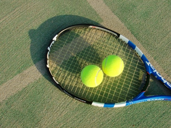 テニスコートにテニスボールが２個ラケットの上に置いてある画像